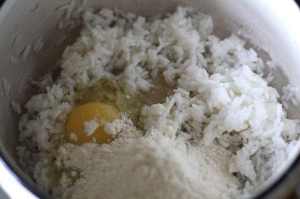 Готовый рис остужаем, взбиваем яйцо и всыпаем муку. Солим и перчим по вкусу
