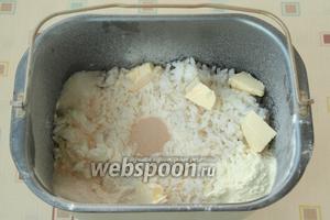 В уголки насыпать сахар, соль и сухое молоко. Нарезать кусочки сливочного масла и разложить сверху риса. По центру сделать углубление и всыпать дрожжи.