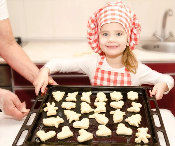 Улыбающаяся маленькая девочка в шляпе повара с противнем печенья Стоковое Изображение