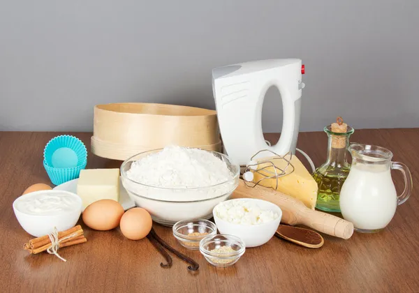 Творог, сметана, сыр, сливочное масло, микшер и торт Пан на столе, на сером фоне Стоковое Фото