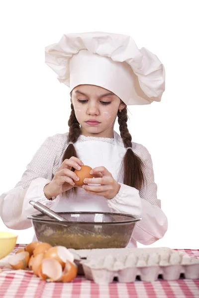 Маленький повар девушка в белый фартук перерывы яйца в глубокое блюдо Стоковое Изображение