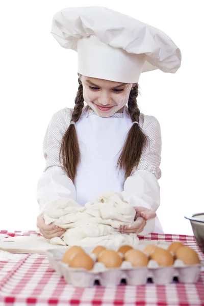 Маленькая девочка в белый фартук и шапку шеф-повара Замесить тесто в го Стоковое Фото
