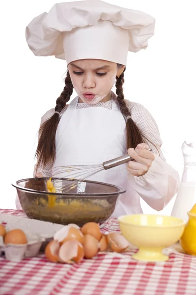 Маленькая девочка в белый фартук ломает возле плиты с яйцами Лицензионные Стоковые Изображения