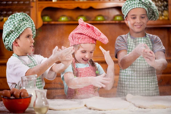 Три смешные ребенка рукопожатие с мукой на кухне Лицензионные Стоковые Изображения