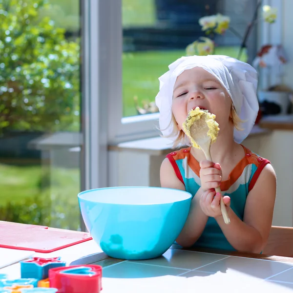 Милая маленькая девочка, выпечки тесто на кухне Лицензионные Стоковые Фото