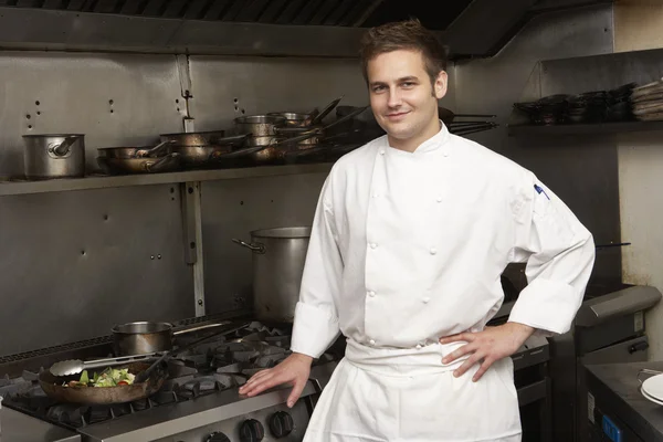 Шеф-повар мужчины стоя рядом с плита в кухне ресторана Стоковое Фото