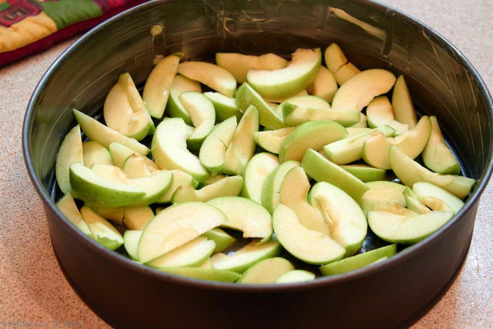 В смазанную сливочным маслом форму выкладываем яблоки и равномерно заливаем их получившимся тестом