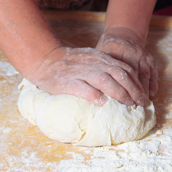 Руки пожилой женщины месят тесто Стоковое Изображение