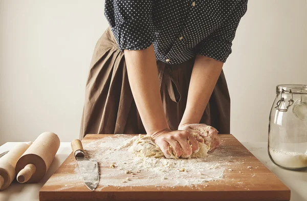 Woman kneads dough for pasta on wooden board Стоковое Изображение