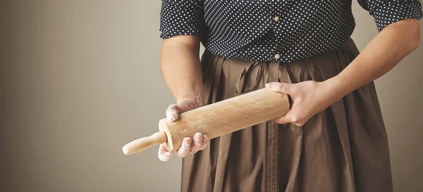 Женщина держит что деревянной скалкой в руках трет муки Стоковое Фото
